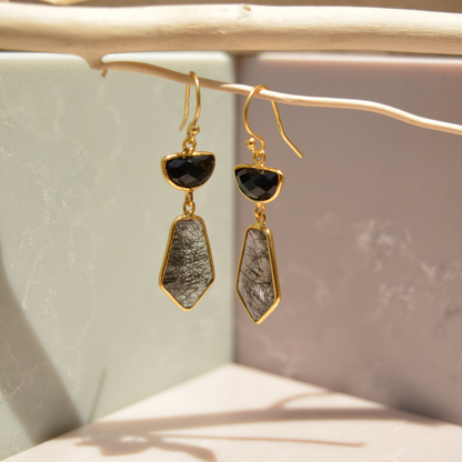 Close-up flat lay of the Midnight Strength Earrings on a white background, highlighting the unique textures of the natural black rutile stones.