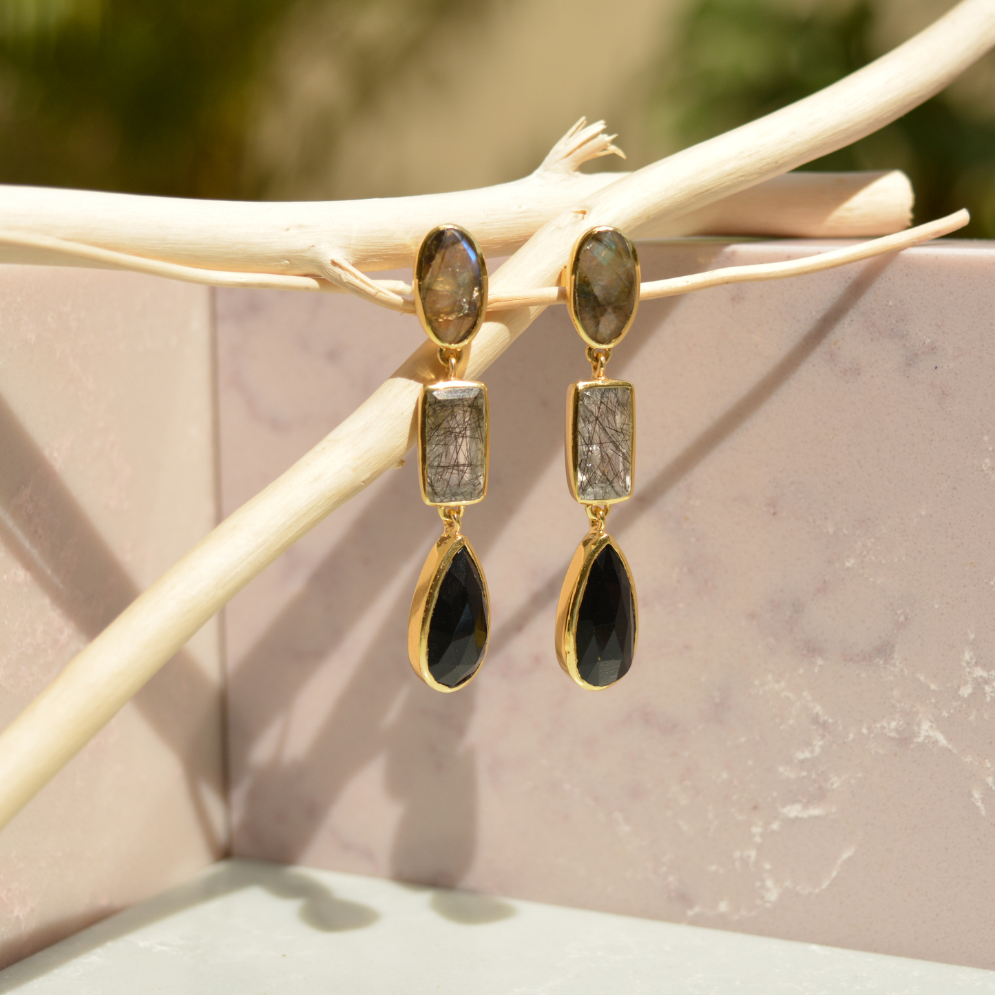 Close-up flat lay of the Midnight Elegance earrings on a white background, showcasing the iridescent labradorite tops and geometric black stone textures.