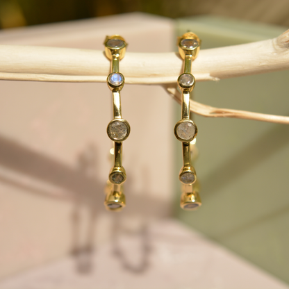 Close-up of the Moonspell Layers earrings hanging on a branch, highlighting the iridescent flashes of the natural labradorite stones.