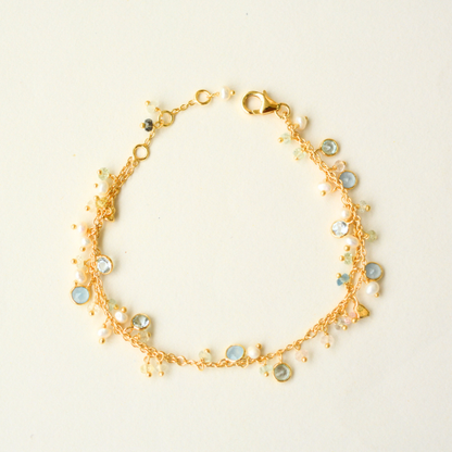 A delicate gold-plated silver double-chain bracelet accented with colorful gemstone and pearl charms, displayed on a clean white background.