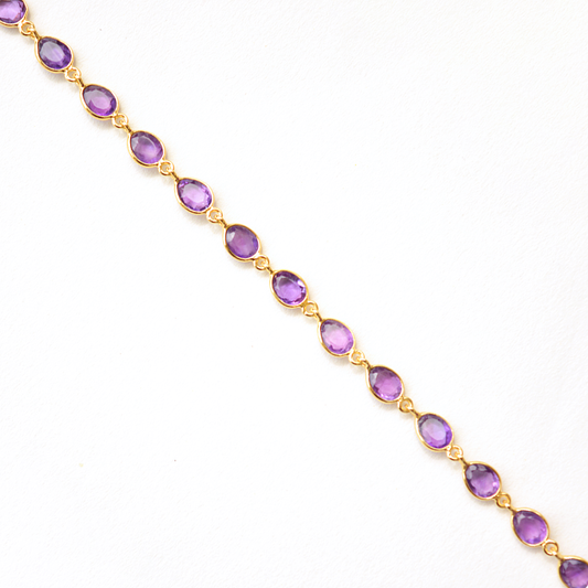Close-up of a minimalist silver bracelet with a vibrant violet gemstone, isolated on white.