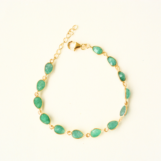 A gold-plated silver chain bracelet featuring multiple oval-cut green beryl stones, photographed against a clean, neutral background.