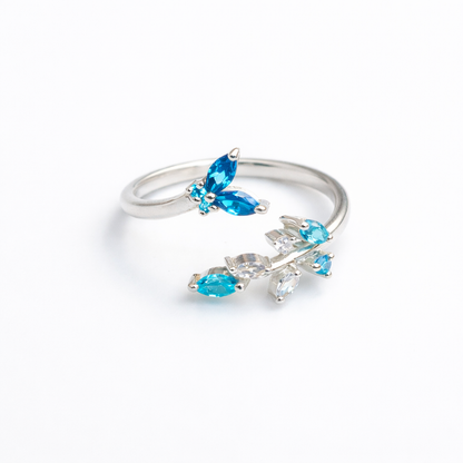 High-polish 925 sterling silver ring featuring a detailed butterfly and flower motif on an adjustable open band.