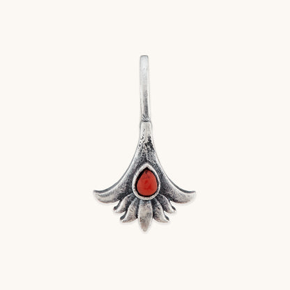 A front-facing studio shot of a symmetrical, floral-themed silver nose clip, showcasing the detailed texture of the metal petals surrounding a vibrant, deep reddish-orange central stone.