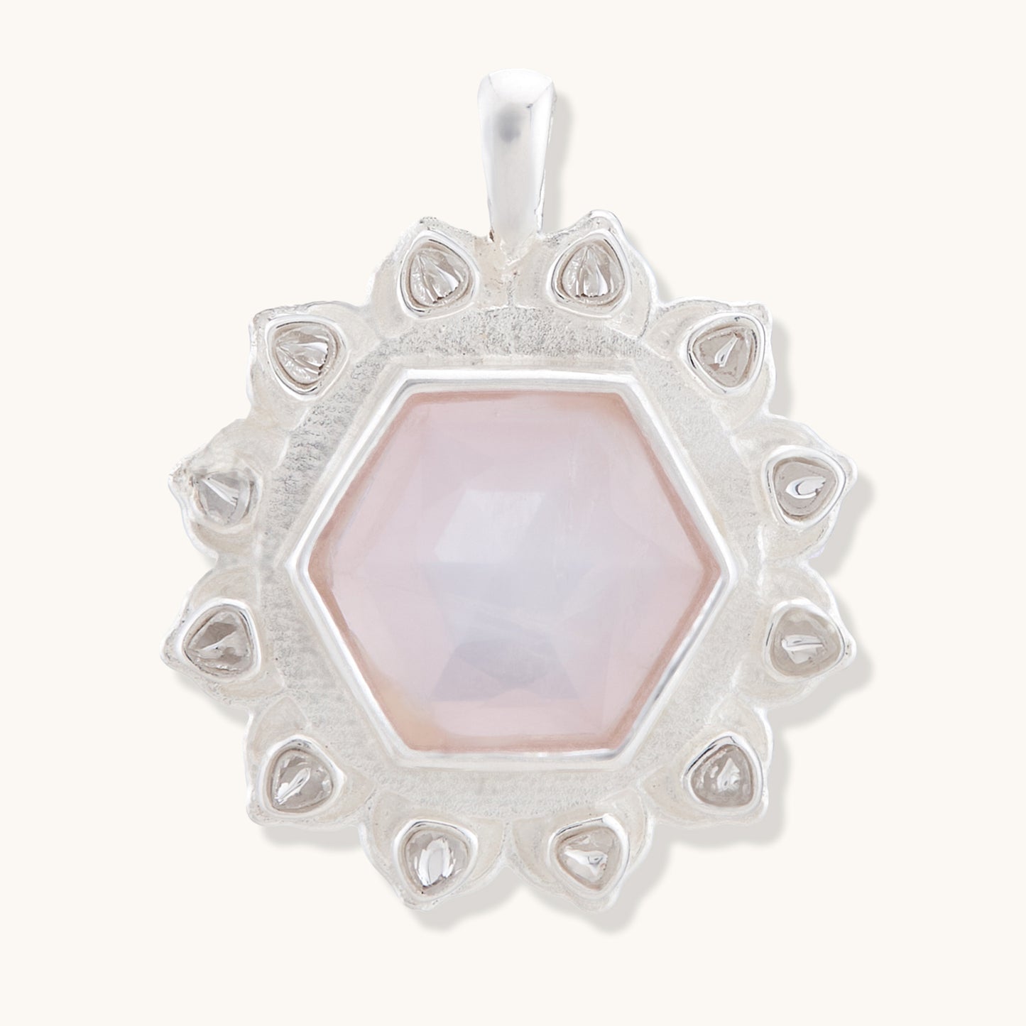 A delicate pendant featuring a soft blush-pink gemstone encased in a sophisticated, intricate silver plated filigree setting.
