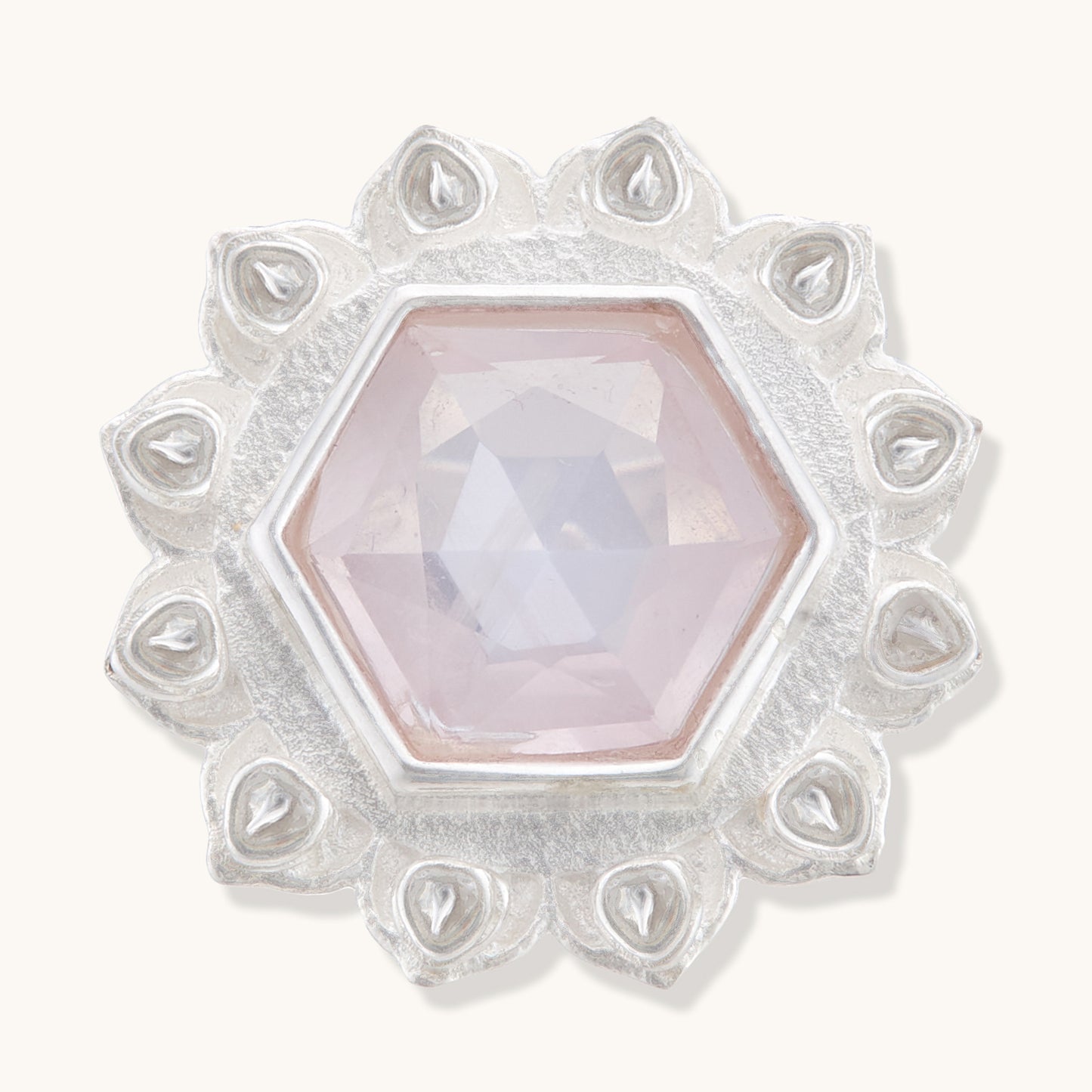 Front view of a silver ring featuring a central hexagonal rose quartz crystal bordered by intricate, teardrop-shaped silver engravings.