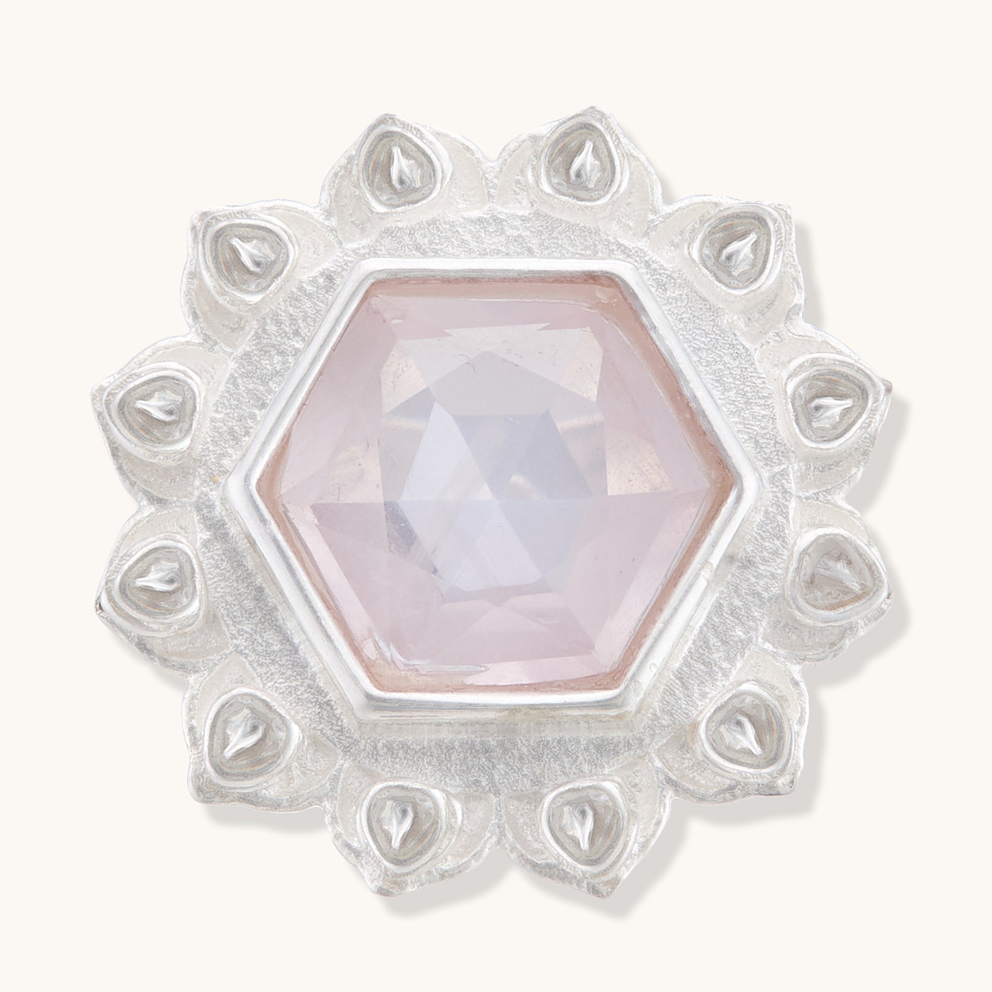 Front view of a silver ring featuring a central hexagonal rose quartz crystal bordered by intricate, teardrop-shaped silver engravings.