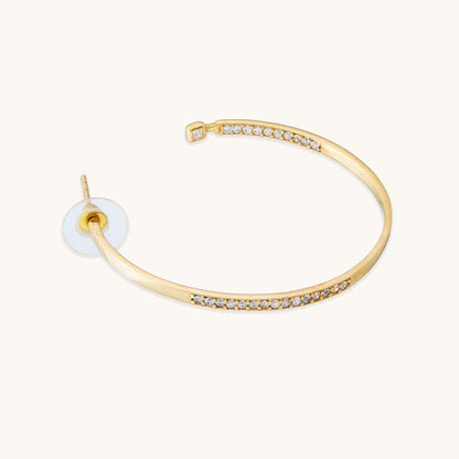 A top-down angle of thick gold huggie hoops, emphasizing their unique, chunky, and wavy structural design.
