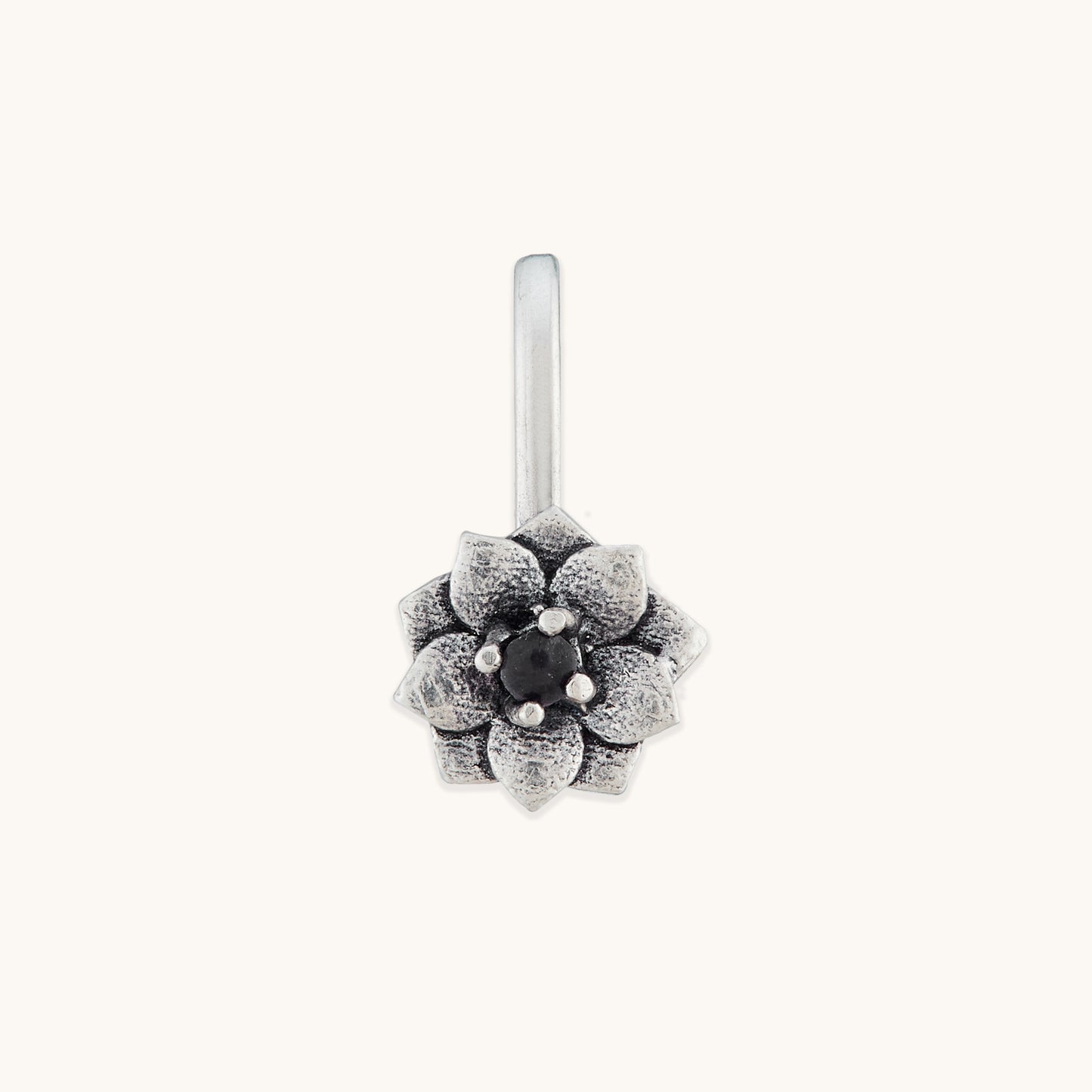 A front-facing studio shot of a silver-toned, floral-shaped nose clip featuring an intricate petal design and a dark, polished center stone.