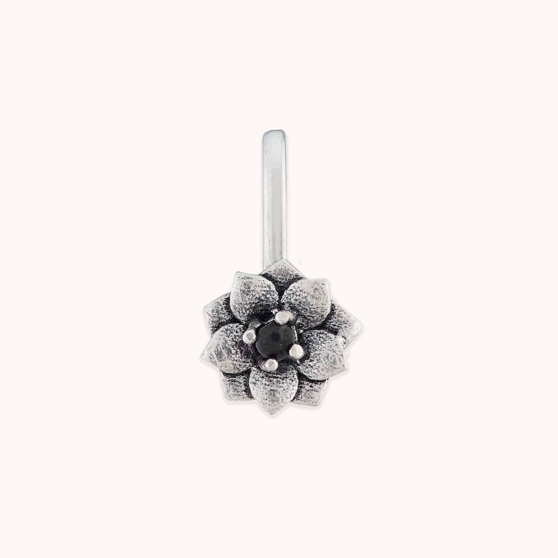 A front-facing studio shot of a silver-toned, floral-shaped nose clip featuring an intricate petal design and a dark, polished center stone.