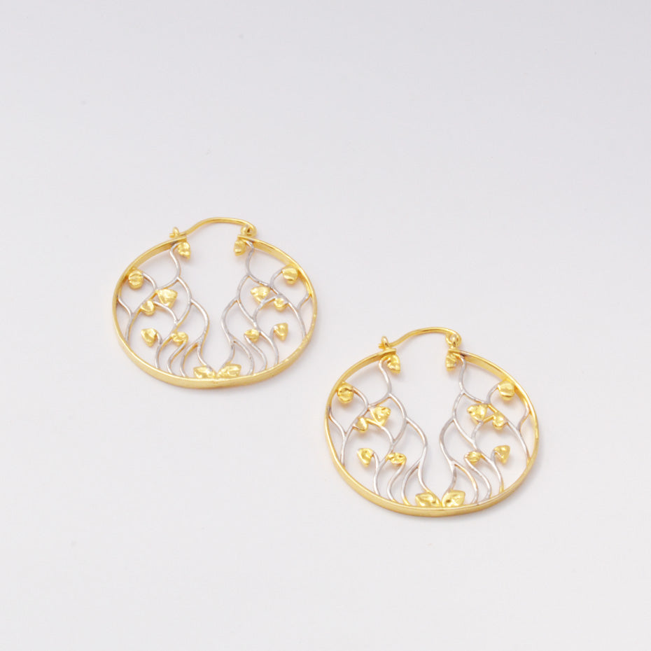 Pair of circular drop earrings featuring a delicate, flowing organic vine design crafted in contrasting gold and silver metal tones.