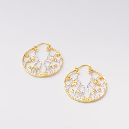 Pair of circular drop earrings featuring a delicate, flowing organic vine design crafted in contrasting gold and silver metal tones.