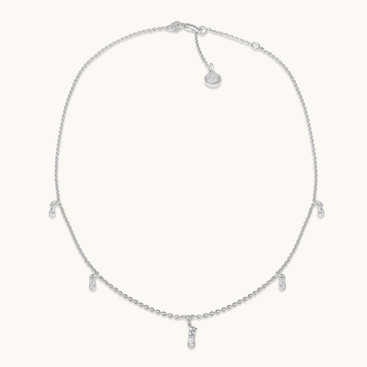 A minimalist silver-plated necklace featuring delicate, spaced-out circular charms that create a refined and airy aesthetic, isolated on a white background.