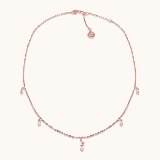 A delicate rose gold-plated chain necklace featuring evenly spaced, small shimmering stations that create an elegant and minimalist floating effect, isolated on a white background.