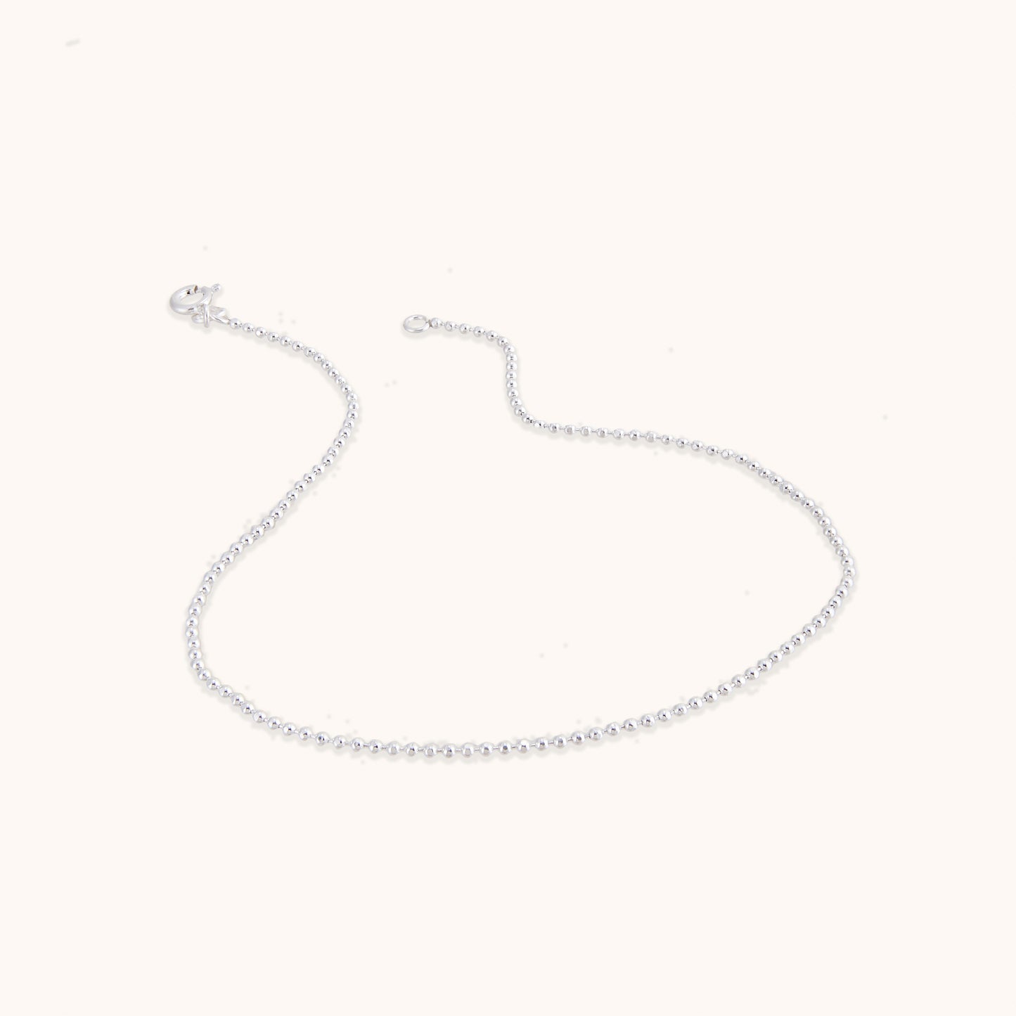 A delicate, minimalist silver chain featuring evenly spaced small beads along the strand, shown with a secure clasp.