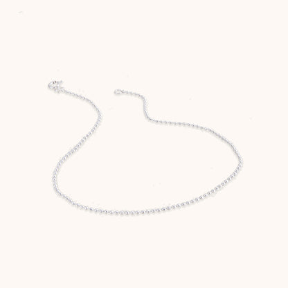 A delicate, minimalist silver chain featuring evenly spaced small beads along the strand, shown with a secure clasp.