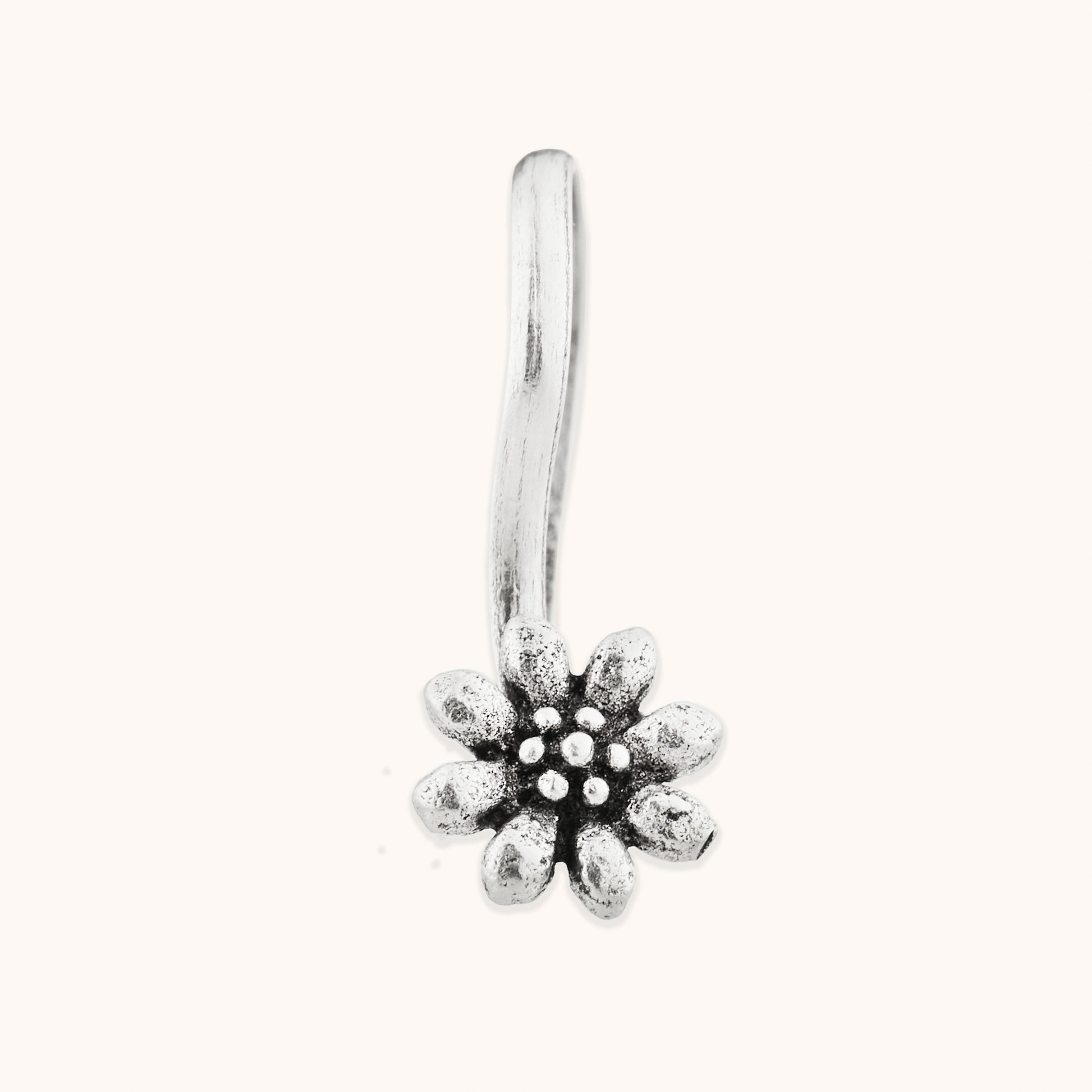 A front-facing view of a decorative, blossom-themed silver nose clip, highlighting the fine texture and precision of the floral-inspired metalwork.