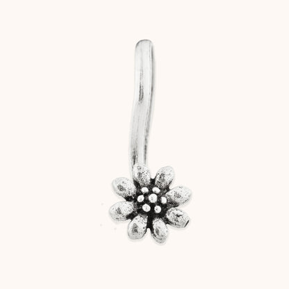 A front-facing view of a decorative, blossom-themed silver nose clip, highlighting the fine texture and precision of the floral-inspired metalwork.