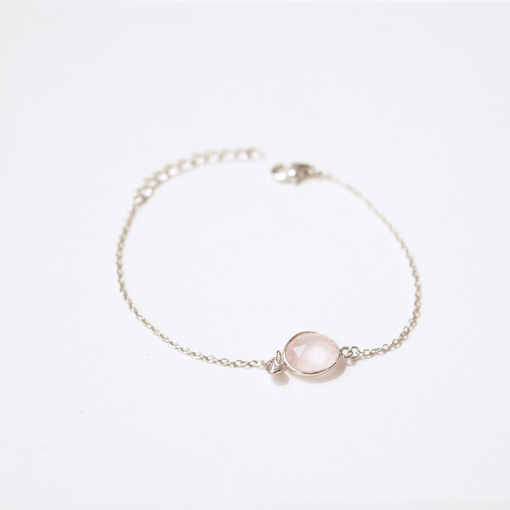 A minimalist sterling silver bracelet featuring a polished, pale pink natural stone, shown with a secure adjustable slider clasp.