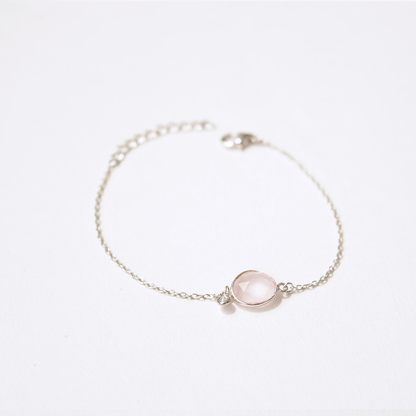 A minimalist sterling silver bracelet featuring a polished, pale pink natural stone, shown with a secure adjustable slider clasp.