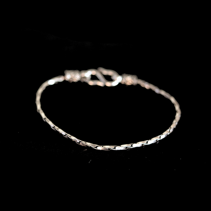 Angled view of a textured silver chain bracelet on a solid black background.
