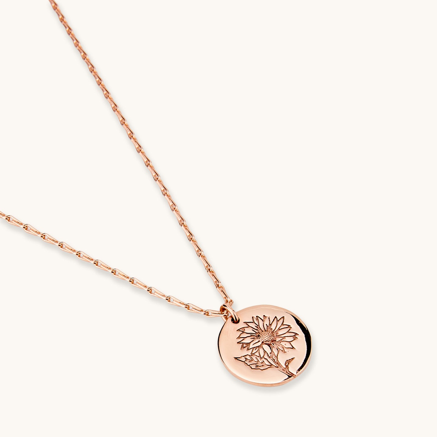 Close-up studio shot of a rose gold Sunflower Medallion pendant featuring an intricate floral engraving, displayed on a clean white background.