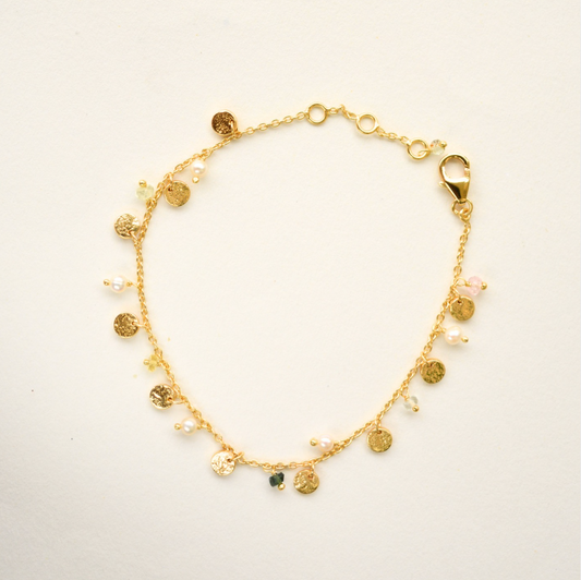 Gold bracelet with charms on a light background