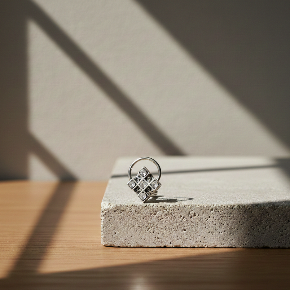 Silver Mirage Nose Pin featuring a square geometric design with inset polki, displayed on a textured stone block in warm natural light.