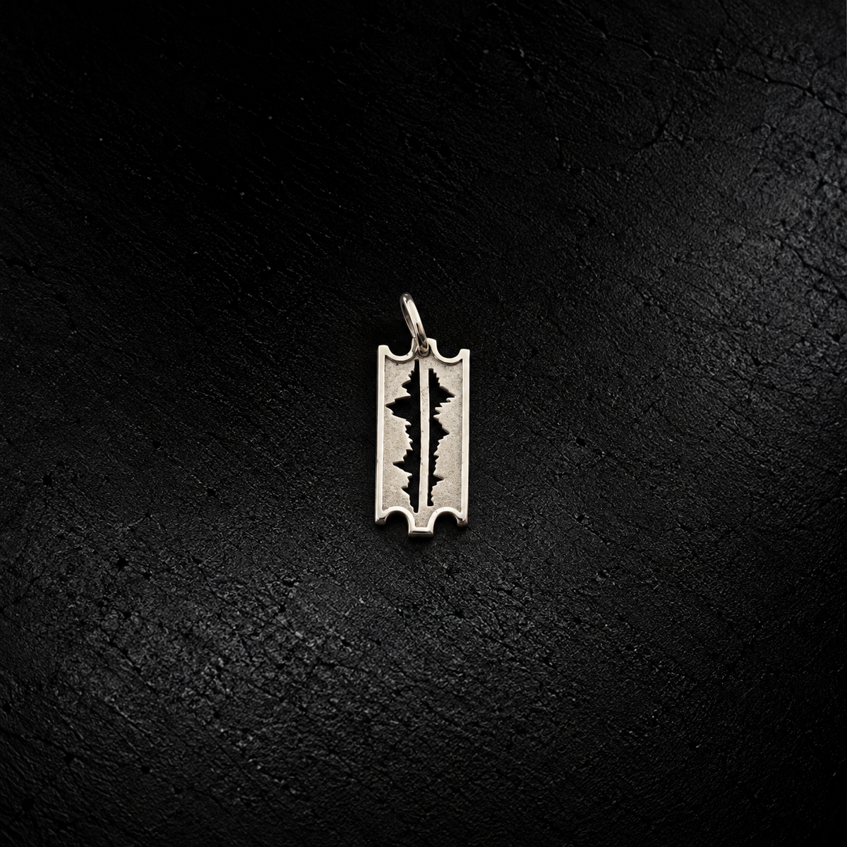 Front view of the small Mountains Are My Lifeline 925 silver razor-edge pendant on dark stone