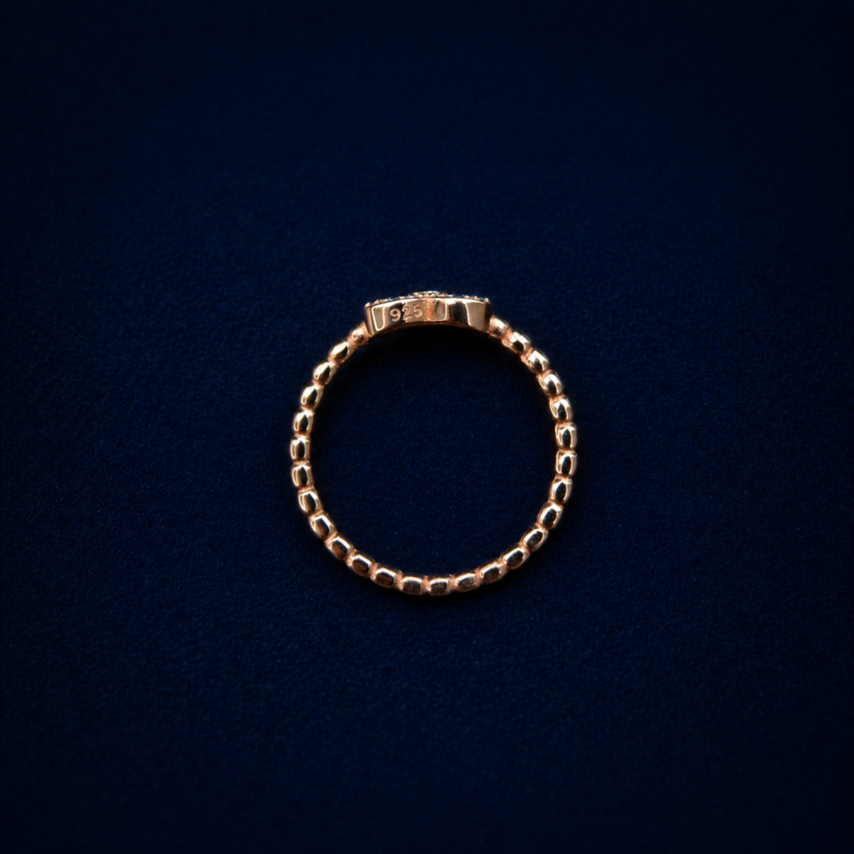 Rear view of the handcrafted A Little Love Ring on a dark navy background, highlighting the authentic 925 sterling silver stamp on the rose gold plated band.