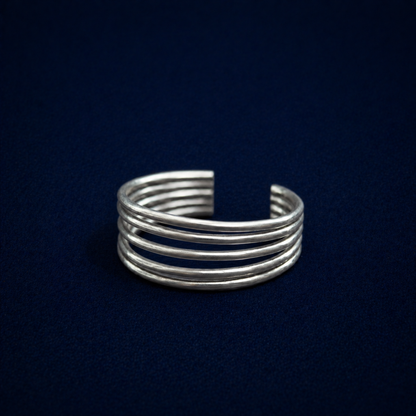 An angled perspective of the handcrafted 925 sterling silver A Little Statement Ring, featuring a modern five-row open wire cuff design on a dark navy background.