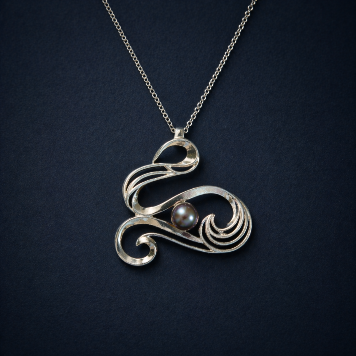 Detailed close-up of the Graceful Flow Necklace, highlighting the luminous blue water pearl nestled within the polished, fluid rhodium-plated silver curves.
