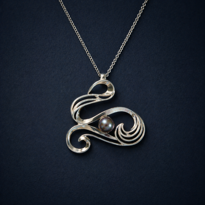 Detailed close-up of the Graceful Flow Necklace, highlighting the luminous blue water pearl nestled within the polished, fluid rhodium-plated silver curves.