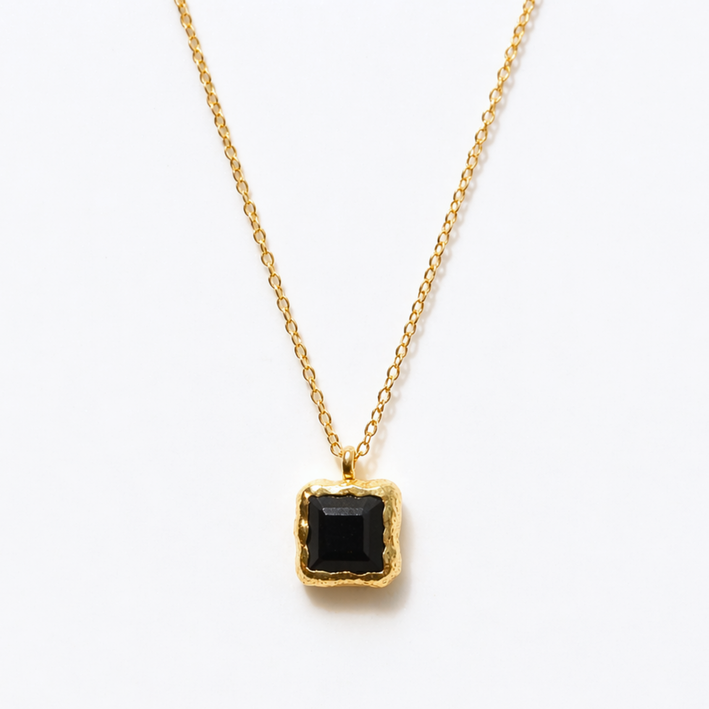 Detailed close-up of the Bold Simplicity necklace highlighting the deep black square onyx stone and the textured, warm golden frame of the handcrafted pendant.