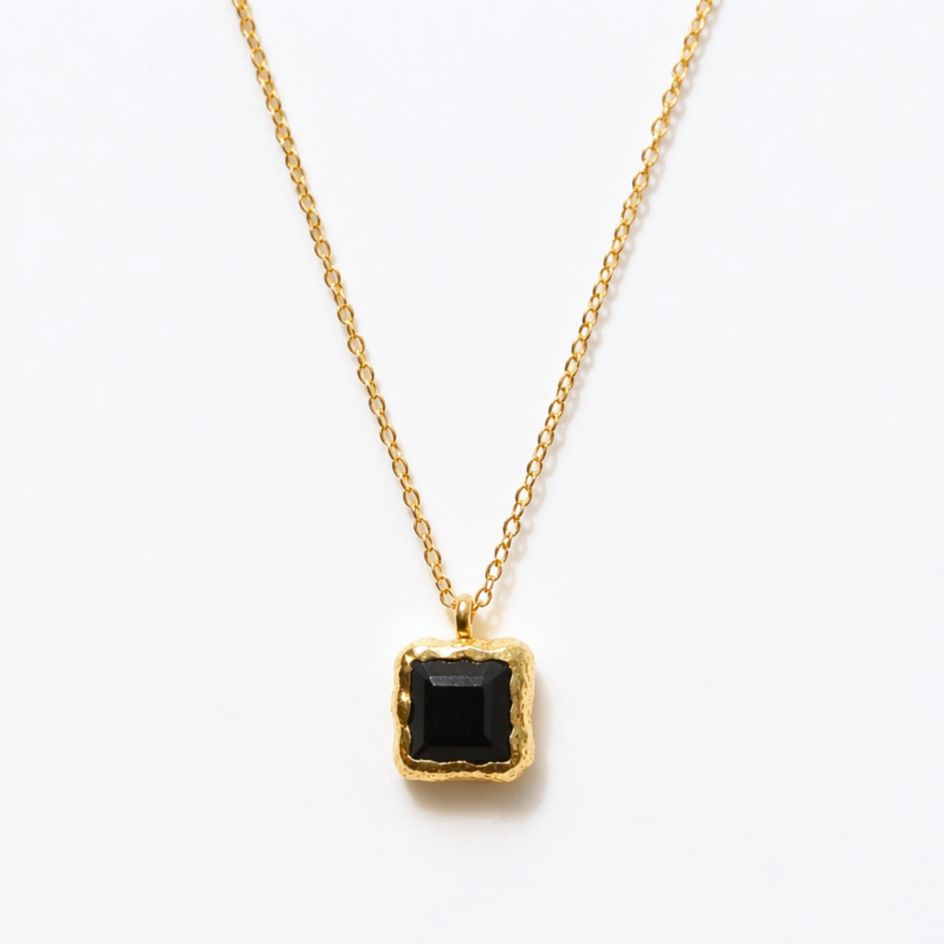 Detailed close-up of the Bold Simplicity necklace highlighting the deep black square onyx stone and the textured, warm golden frame of the handcrafted pendant.