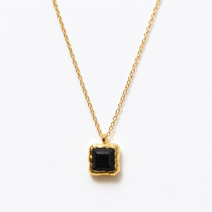 Detailed close-up of the Bold Simplicity necklace highlighting the deep black square onyx stone and the textured, warm golden frame of the handcrafted pendant.