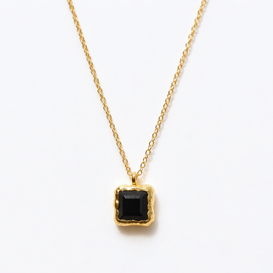 Detailed close-up of the Bold Simplicity necklace highlighting the deep black square onyx stone and the textured, warm golden frame of the handcrafted pendant.