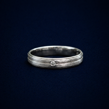 Close-up studio shot of the Glimmer Touch Ring highlighting the tiny, brilliant-cut cubic zirconia stone nestled within a modern textured sterling silver band.