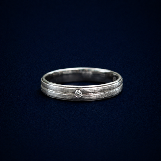 Close-up studio shot of the Glimmer Touch Ring highlighting the tiny, brilliant-cut cubic zirconia stone nestled within a modern textured sterling silver band.