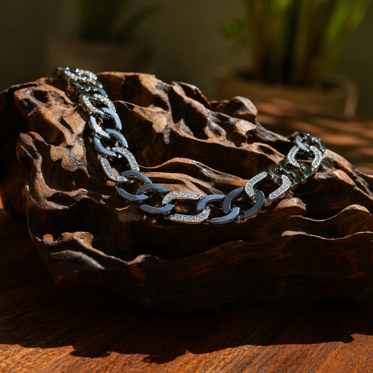 A handcrafted 925 sterling silver Effortless Edge bracelet with thick, rugged links draped over a natural dark wood sculpture, showcasing its bold and raw aesthetic.