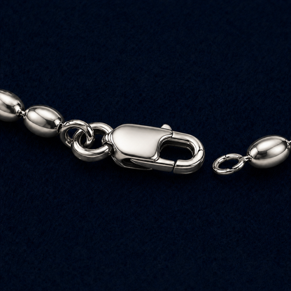 A close-up technical shot of the Effortless Shine anklet in 925 sterling silver, highlighting the high-polish finish of the oval links and the secure lobster clasp closure on a dark navy background.