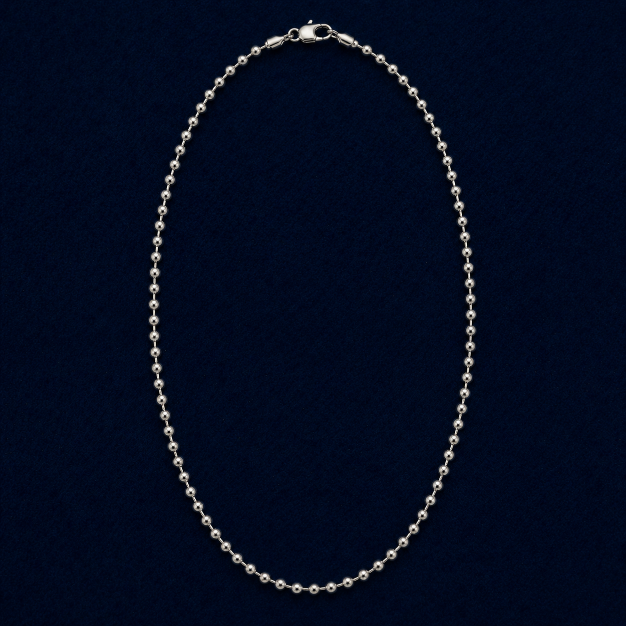 A full studio shot of the handcrafted Everyday Soft Glow necklace in 925 sterling silver, featuring a long, high-polish beaded ball chain design on a dark navy background.