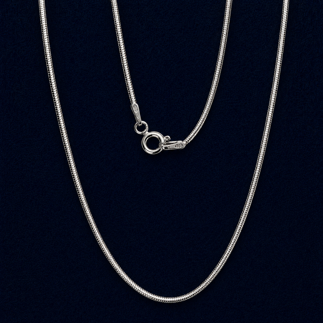 A long  handcrafted 925 sterling silver flat snake chain necklace displayed in a vertical layout, showing its fluid movement and sleek polished finish against a dark background.