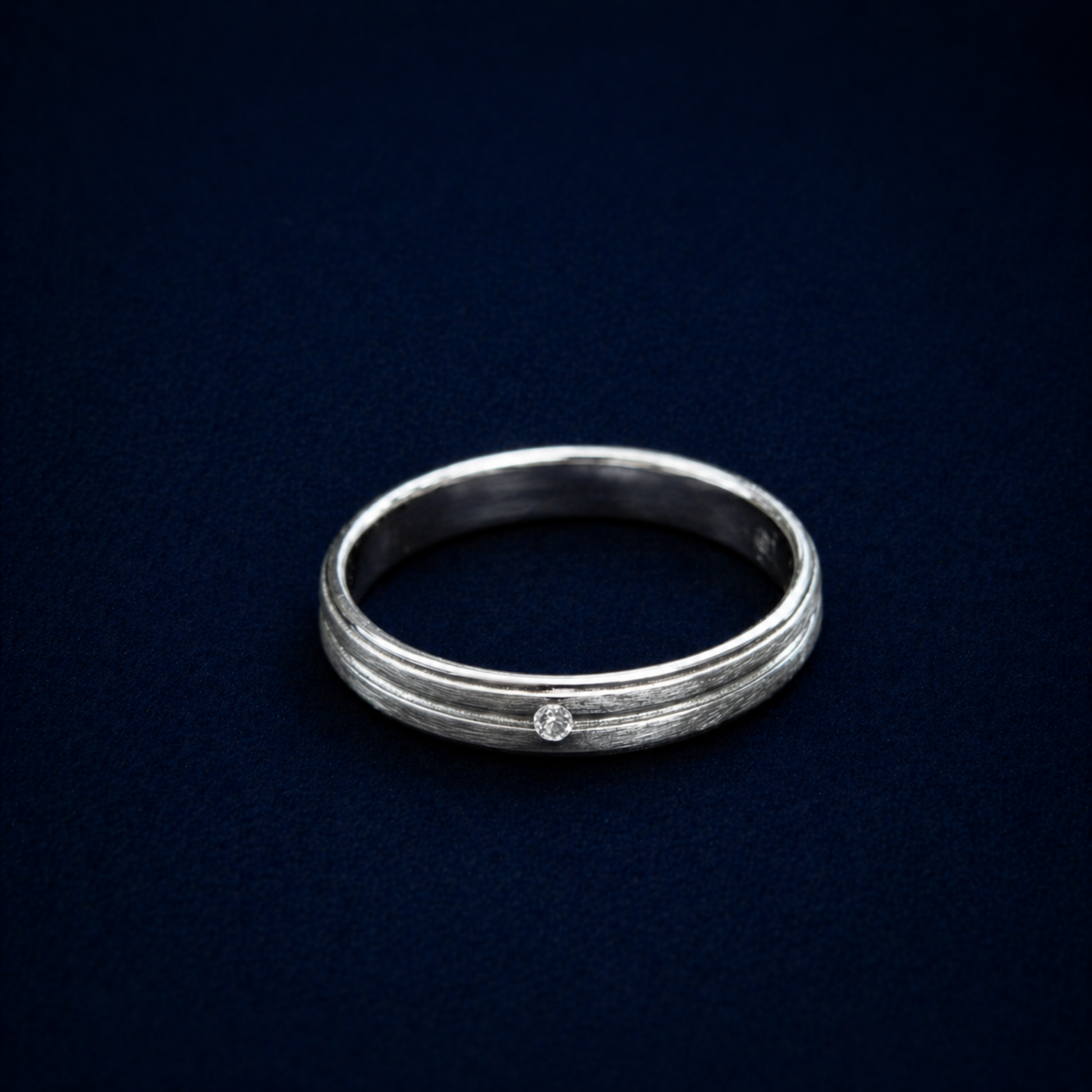 An angled shot of the handcrafted Glimmer Touch Ring in 925 sterling silver, featuring a subtle textured band and a single shimmering cubic zirconia stone.