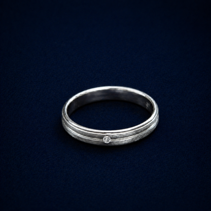 An angled shot of the handcrafted Glimmer Touch Ring in 925 sterling silver, featuring a subtle textured band and a single shimmering cubic zirconia stone.