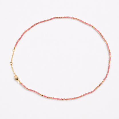 A full studio shot of the Everyday Glow necklace on a white background, displaying the delicate beaded strand and the adjustable 18kt gold plated lobster clasp.
