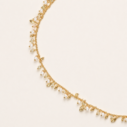 A detailed close-up of the Natural Grace necklace highlighting the rhythmic arrangement of small white pearls, earthy granite beads, and tiny gold leaf-shaped charms on a fine gold-plated chain.