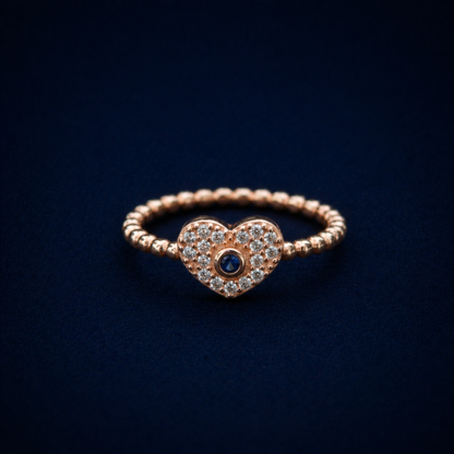 Frontal view of the A Little Love Ring featuring a sparkling pavé-set heart with a central blue cubic zirconia stone on a polished rose gold plated silver band.