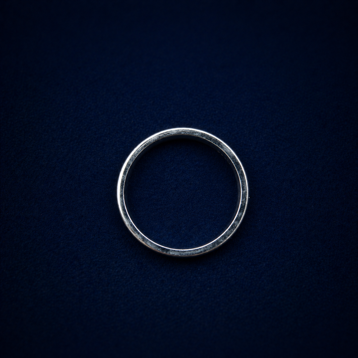A top-down view of the Midnight Trio Ring on a dark navy textured background, showcasing the clean circular silhouette and modern minimal design.