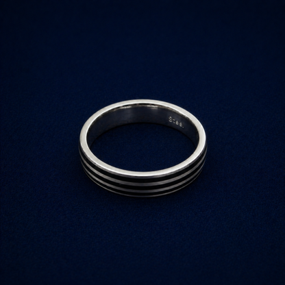An angled shot of the handcrafted Midnight Trio Ring, highlighting the three sleek black enamel parallel lines inlaid into a polished 925 sterling silver band.